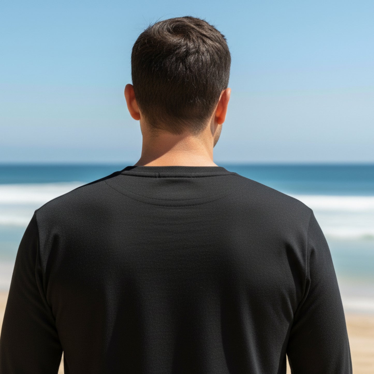 Man wearing a  Dew 100% Cotton black shirt standing on a beach with ocean view