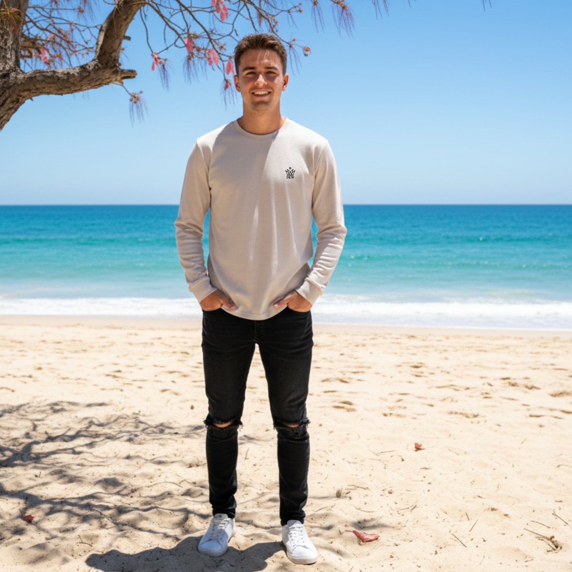 Person wearing Dew 100 % cotton sea grey tshirt standing on a beach with ocean and clear sky in the background