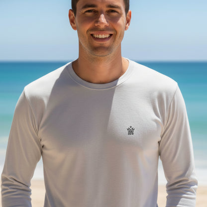 Man wearing a Dew 100 % cotton sea gray long-sleeve shirt with a logo on a beach