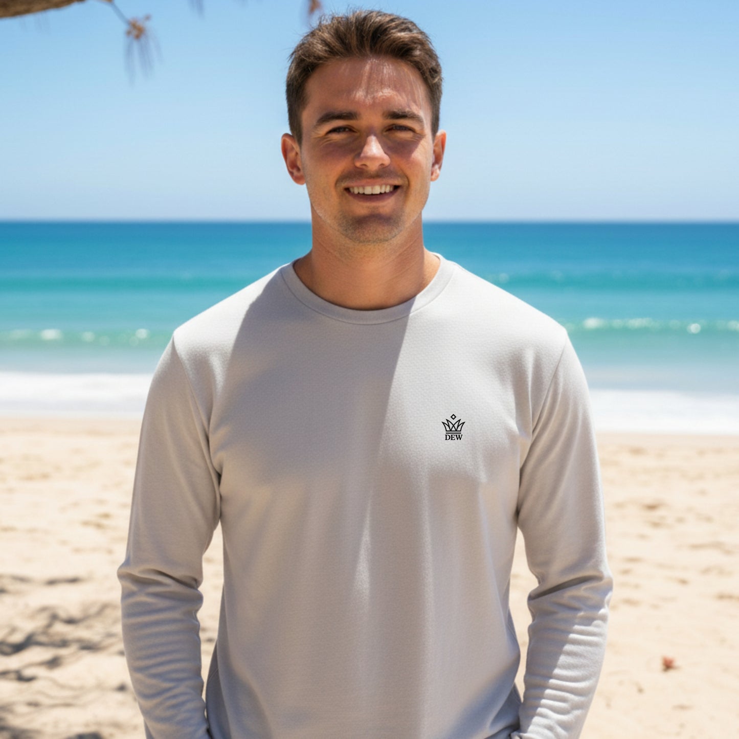 Man wearing a Dew 100% cotton sea gray long-sleeve shirt with a logo on a beach