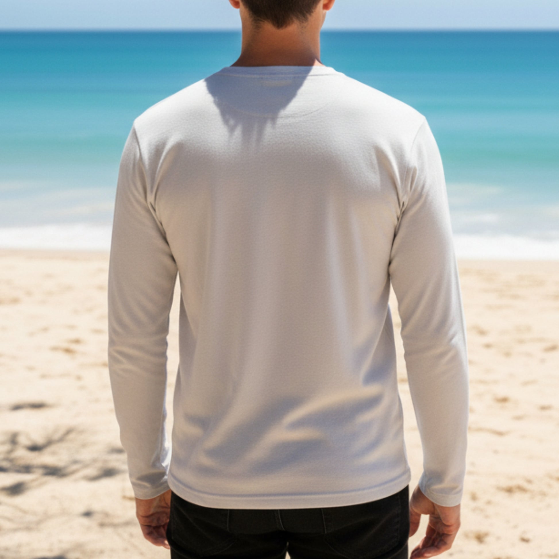 Person wearing a Dew 100 % cotton white long-sleeve shirt on a beach with clear blue water.