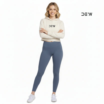 Woman wearing a beige hoodie and Dew Core fit high waited leggings ocean mist with 'DEW' branding on a white background