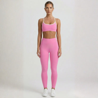 Woman wearing a pink Dew Elevate Bra athletic outfit on a plain background