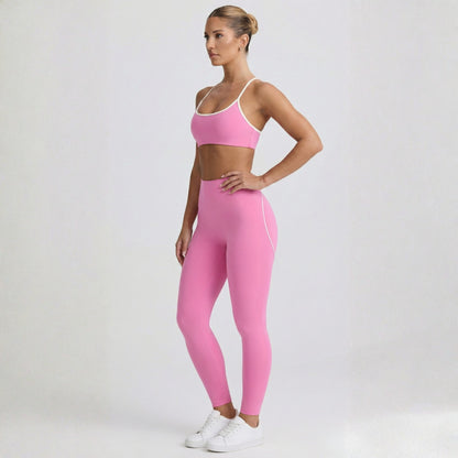 Woman wearing a pink Dew Elevate Bra - pink sports bra and leggings set on a white background