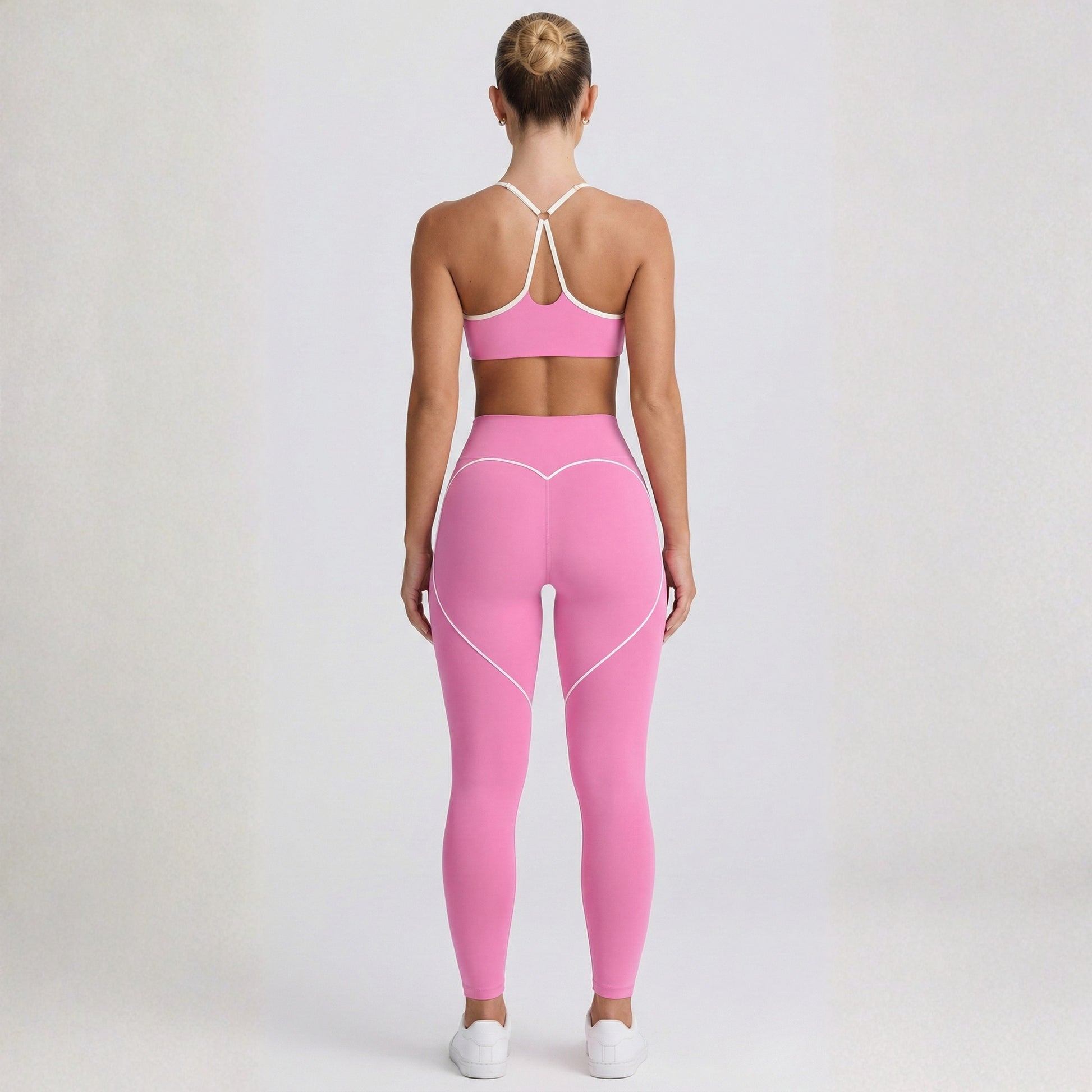 Person wearing a pink Dew Elevate Bra -sports bra and leggings set on a plain background