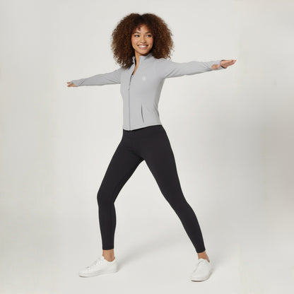 Woman wearing a Dew Grey Flex UPF50+ Performance Jacket  zip-up jacket and black leggings on a white background