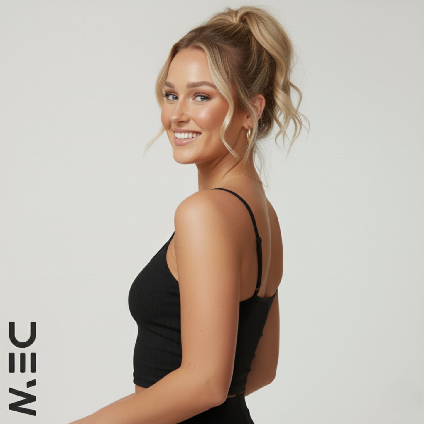 Woman wearing a black DEW luxe cami top with a neutral background and 'DEW' branding.