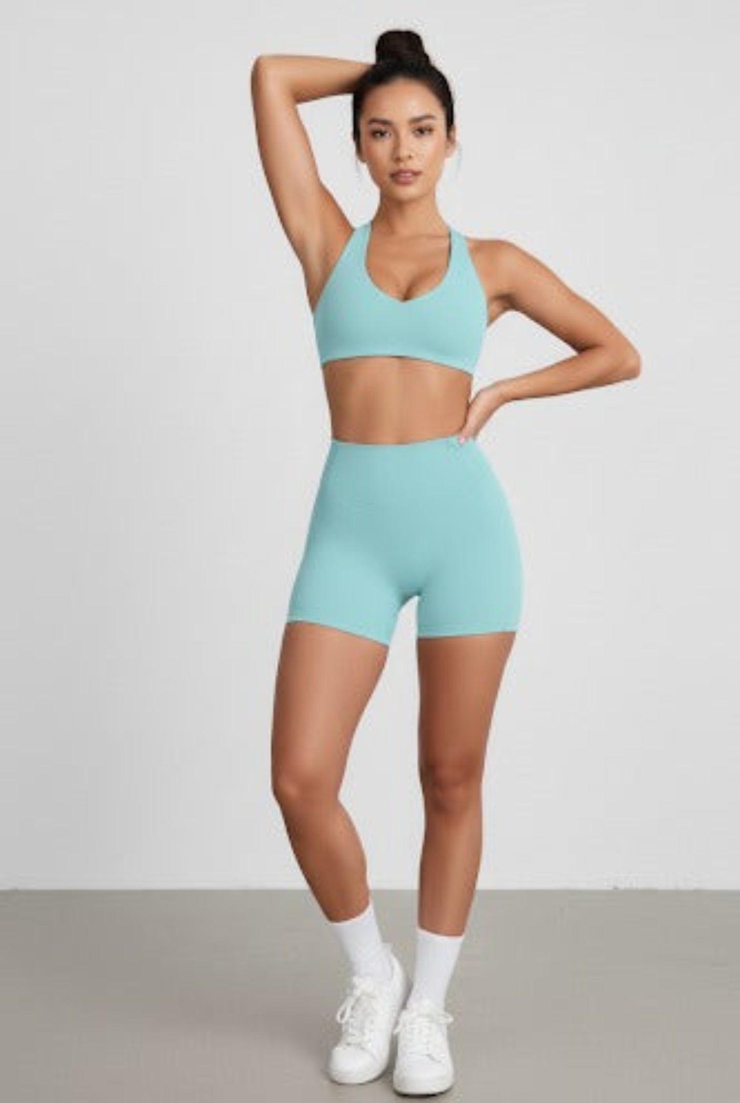 Woman wearing a light blue athletic outfit on a plain background