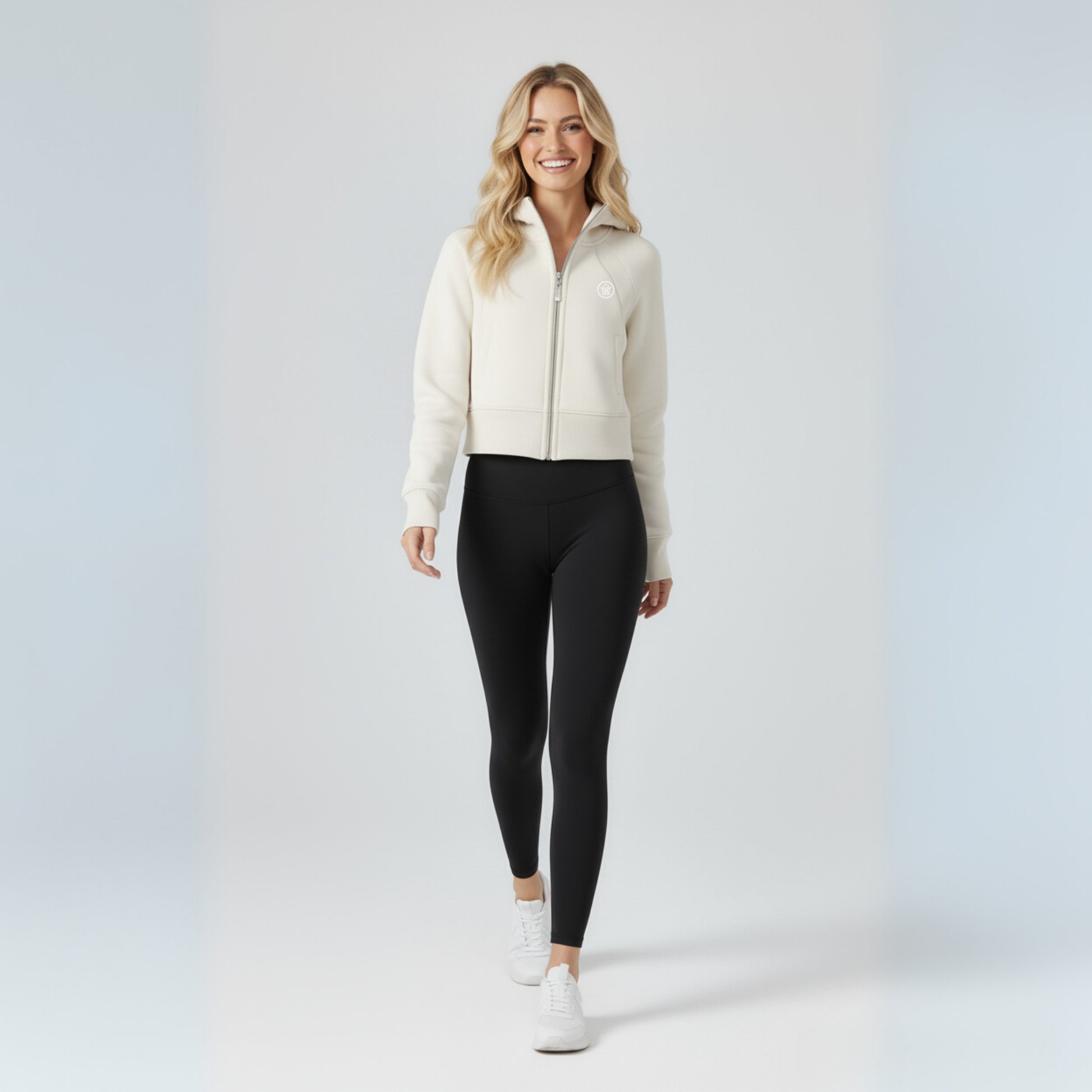 Woman wearing a white jacket and black Dew high waisted leggings on a light gray background