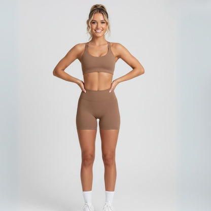 Woman wearing a Dew coco heart flex sports bra and shorts set on a light gray background