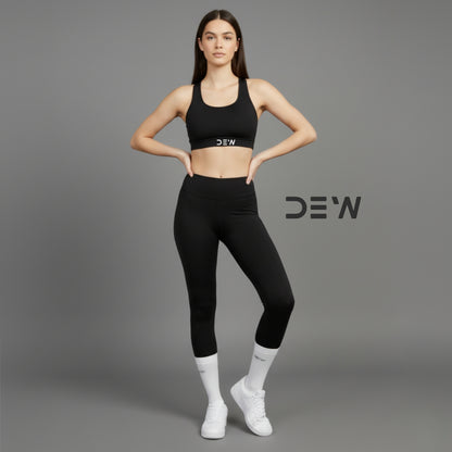 Woman wearing black sports bra and leggings and Dew White Socks with 'DEW' branding on a gray background