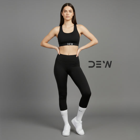 Woman wearing black sports bra and leggings and Dew White Socks with 'DEW' branding on a gray background
