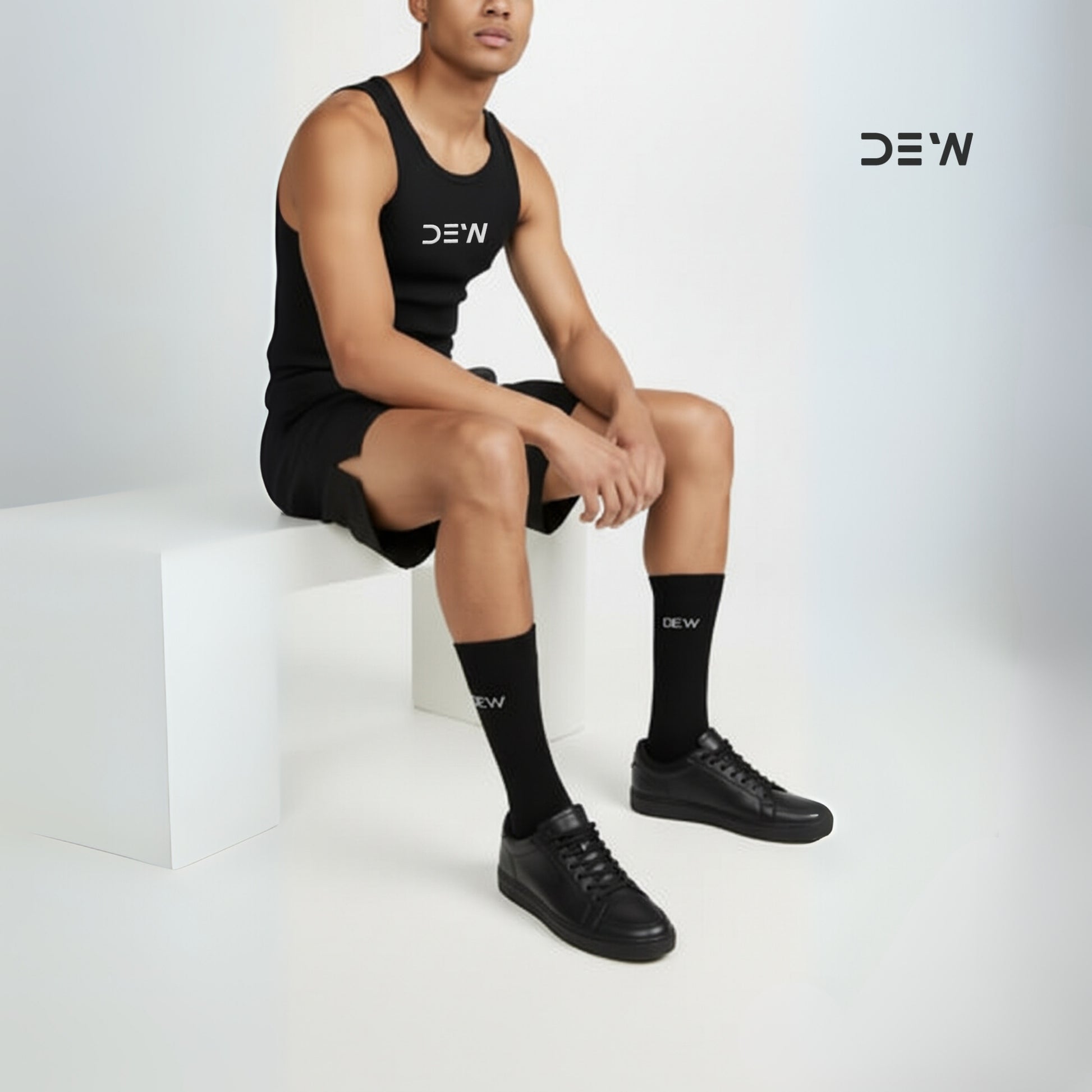 Person wearing black tank top, shorts, and socks with 'DEW' branding on a white background.