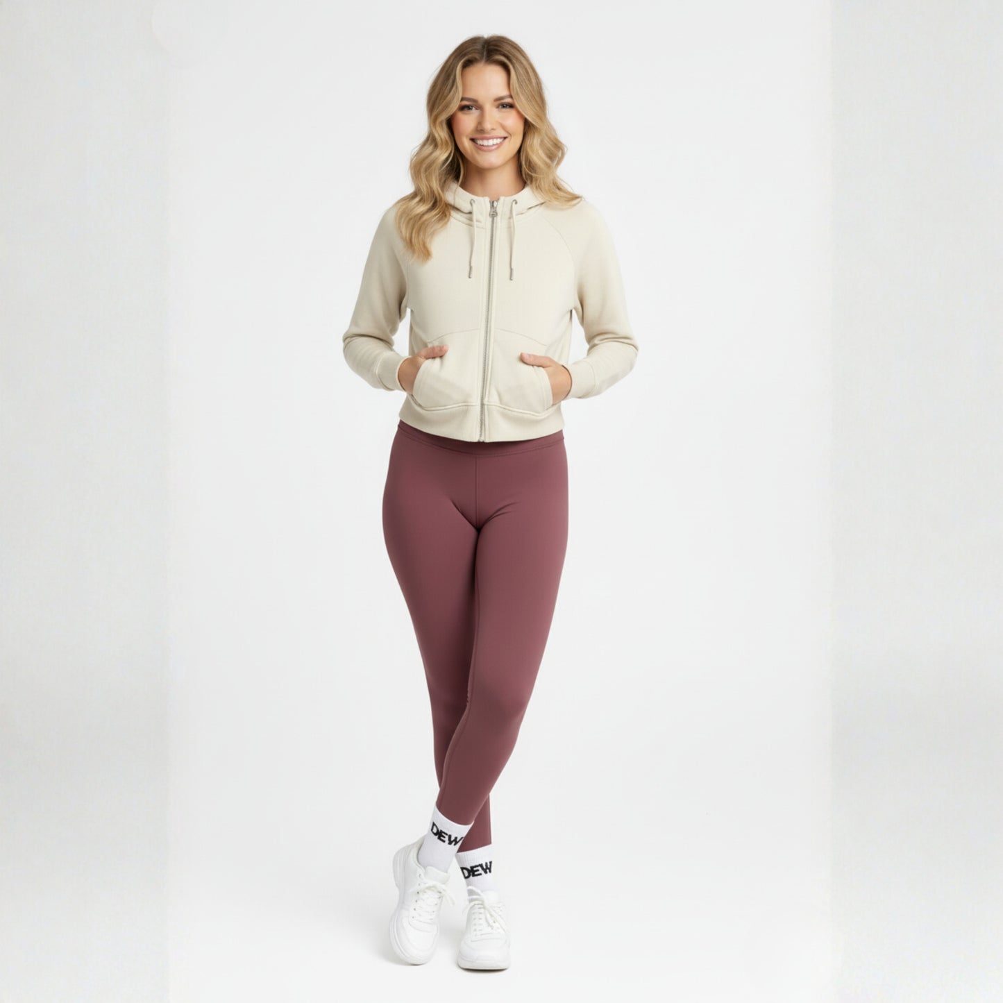 Woman wearing a beige hoodie and Dew dusty plum high waisted leggings on a white background