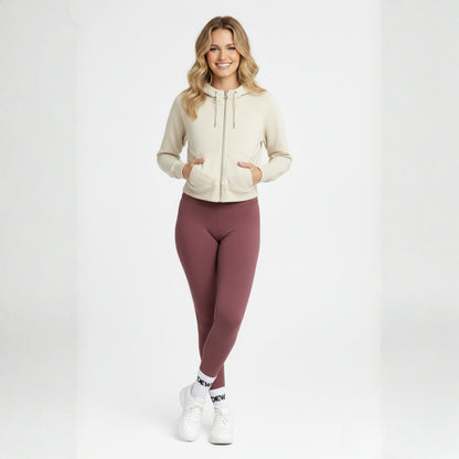 Woman wearing a beige hoodie and Dew dusty plum high waisted leggings on a white background
