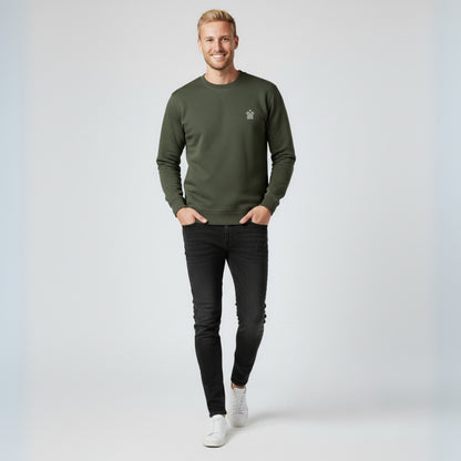 Man wearing a Dew olive green  crewneck jumper and black jeans on a white background