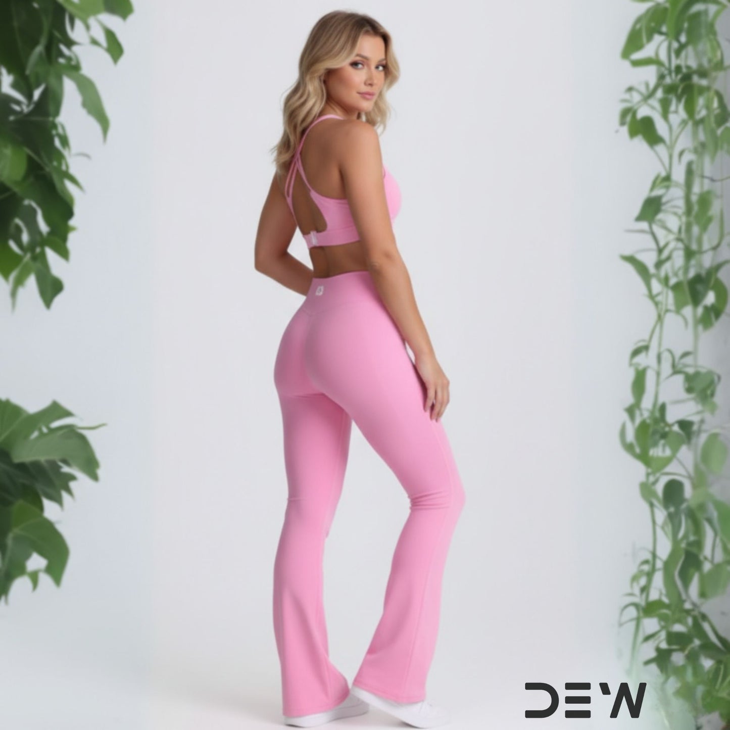 Woman in rear view wearing pink seamless sports bra and Flow Fit Flare leggings. Image highlights high-waist fit and leg-lengthening flare design.
