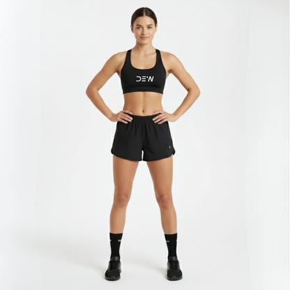 Woman wearing a black sports bra and shorts with 'DEW' branding on a white background