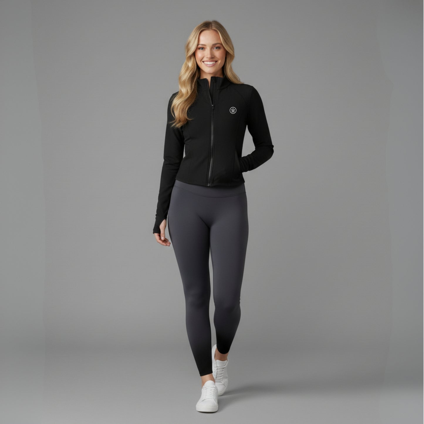 Woman wearing a black Flex UPF50+ Performance Jacket and gray leggings on a gray background
