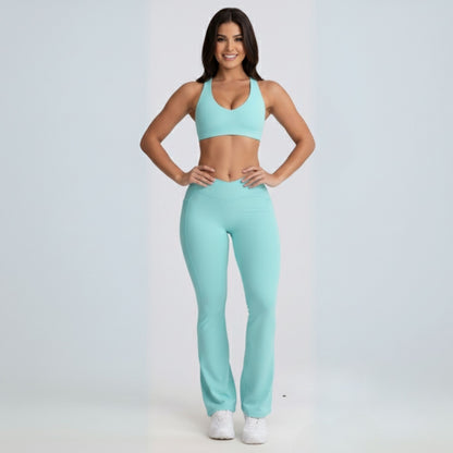 Woman wearing a matching mint Dew Flow fit flares sports bra and leggings set on a light gray background