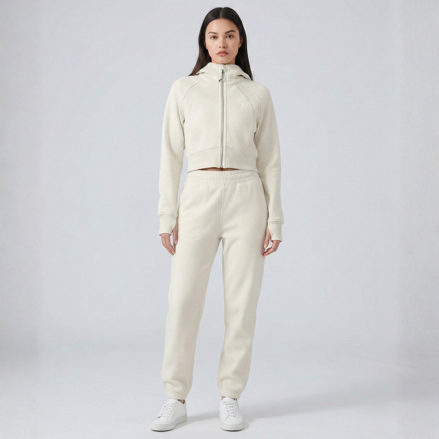 Person wearing a cream-colored Dew Women's Premium Crop Zip Jacket tracksuit on a white background
