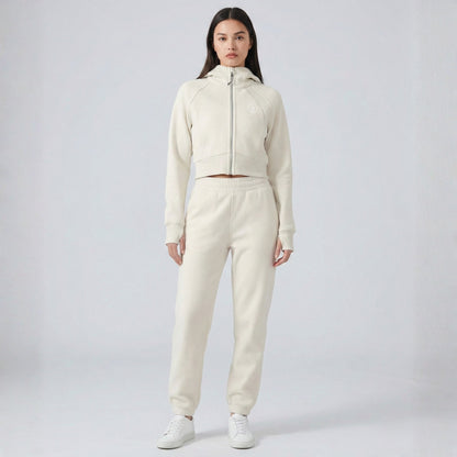 Person wearing a cream-colored Dew Women's Premium Crop Zip Jacket tracksuit on a white background