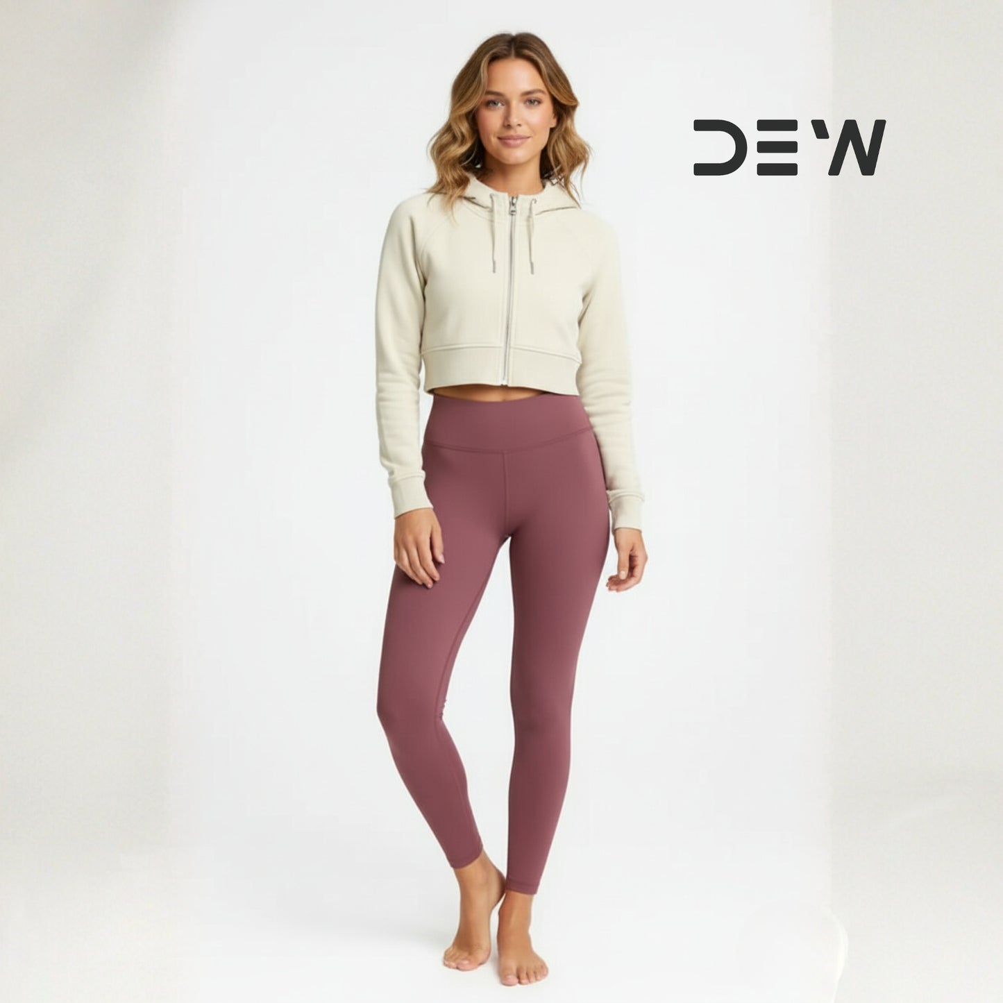 Woman wearing a beige hoodie and Dew dusty plum leggings on a white background with 'DEW' logo.