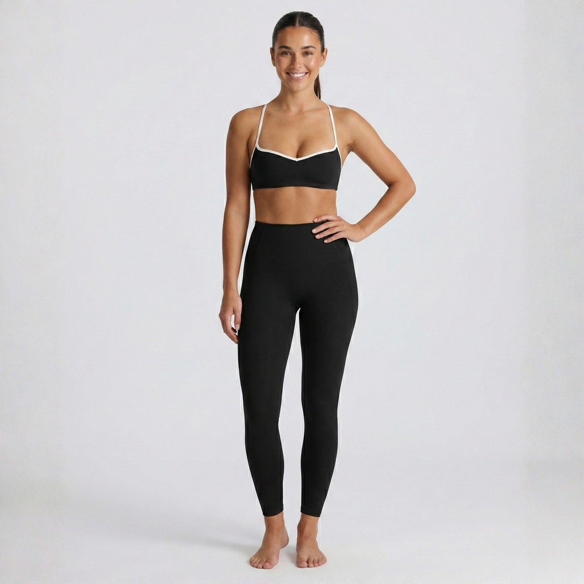 Woman wearing a black DEW Elevate sports bra and leggings on a white background