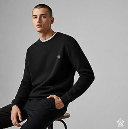 Man wearing a  black Dew Classic Jumper with a logo on a gray background