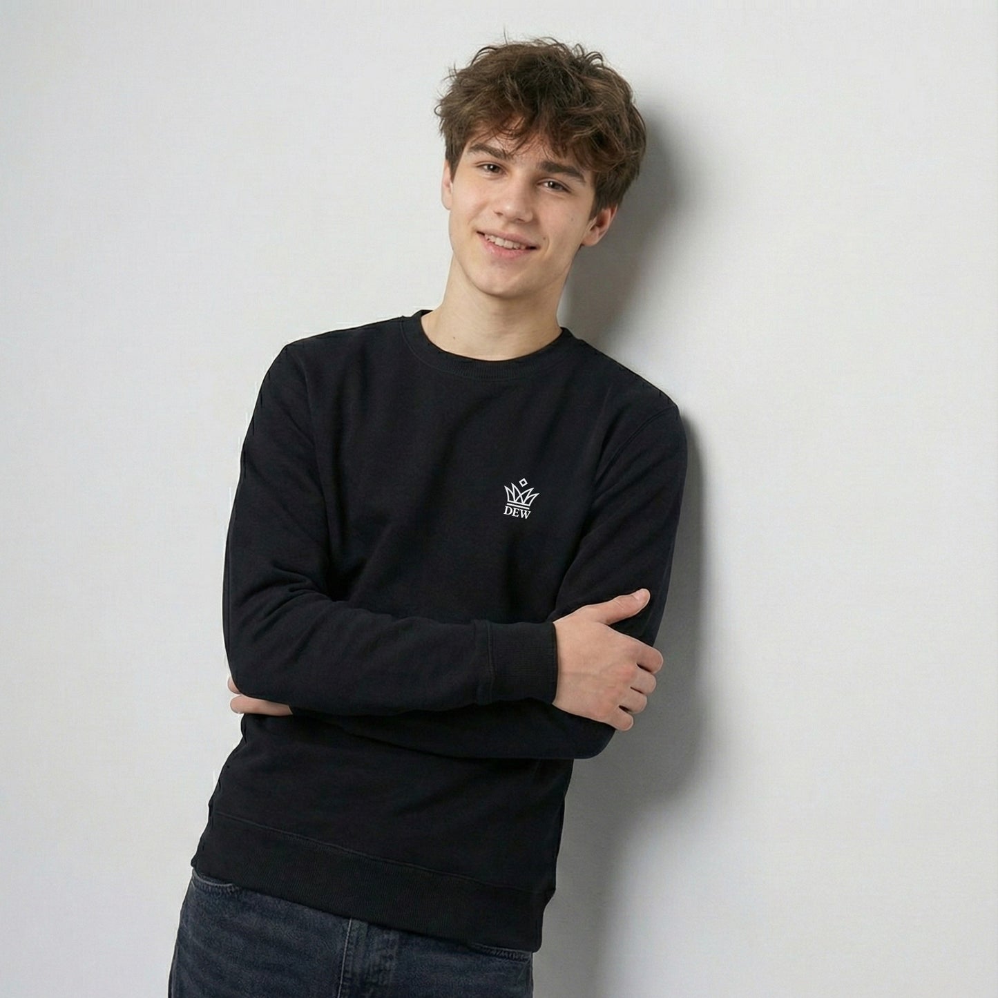 Person wearing a black Dew Classic Jumper with a logo against a light gray background