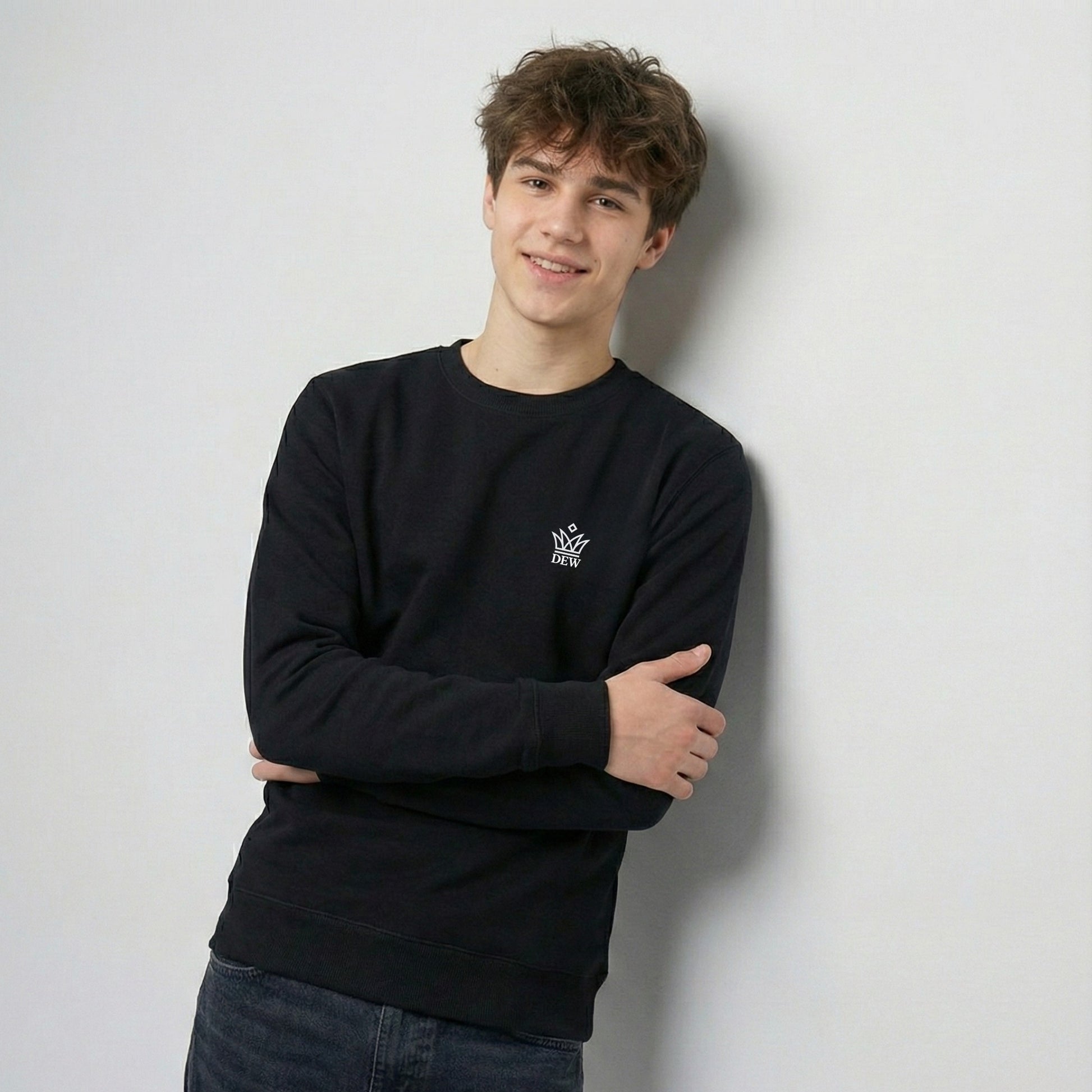 Person wearing a black Dew Classic Jumper with a logo against a light gray background