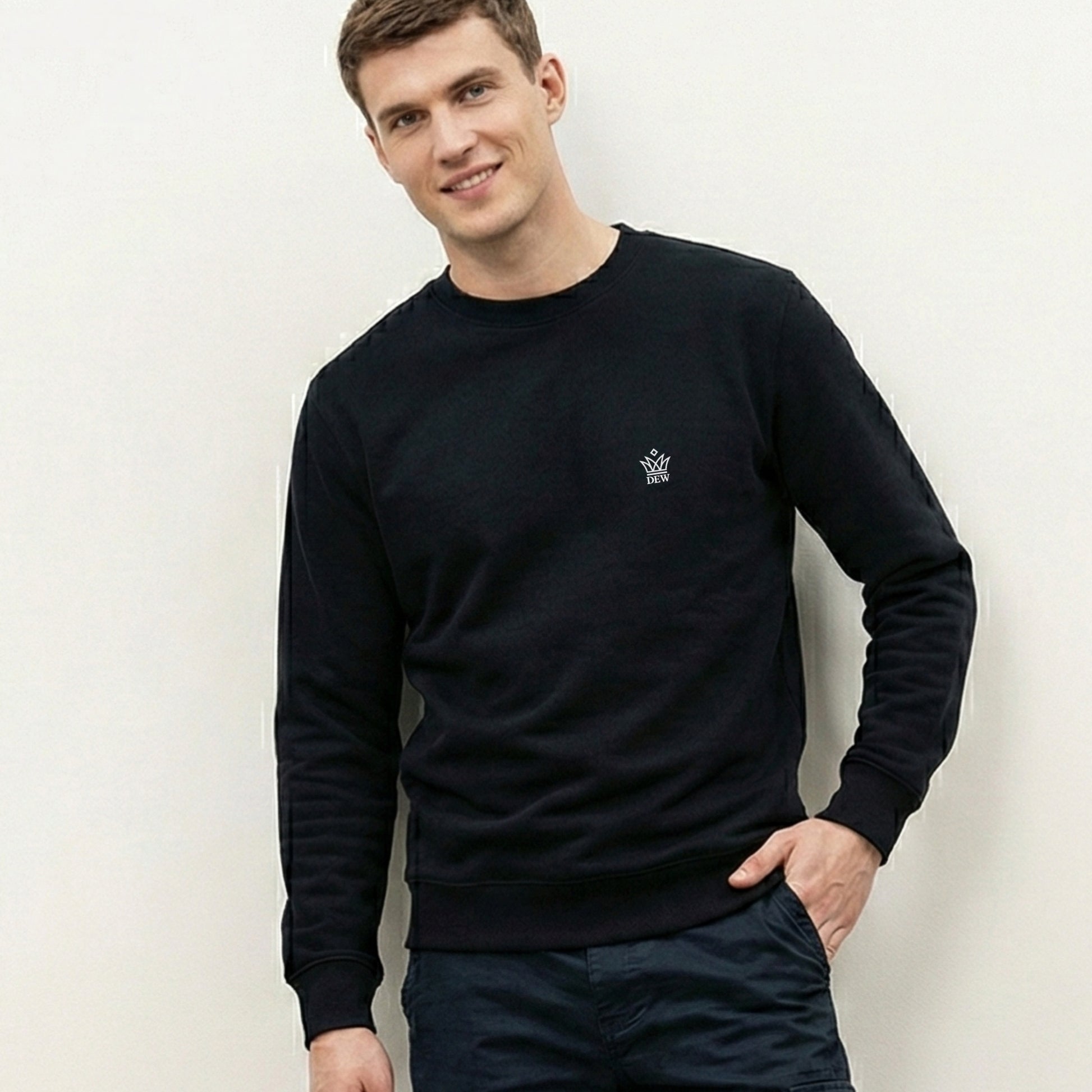 Man wearing a  black Dew Classic Jumper with a small logo against a plain background