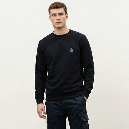 Man wearing a  black Dew Classic Jumper with a small logo on a plain background