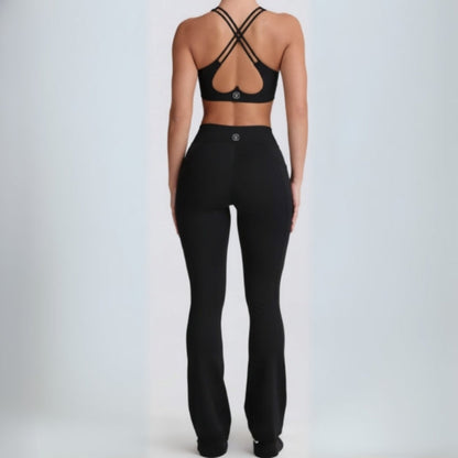 Person wearing a black  black dew flow fit flares sports bra and leggings on a light gray background