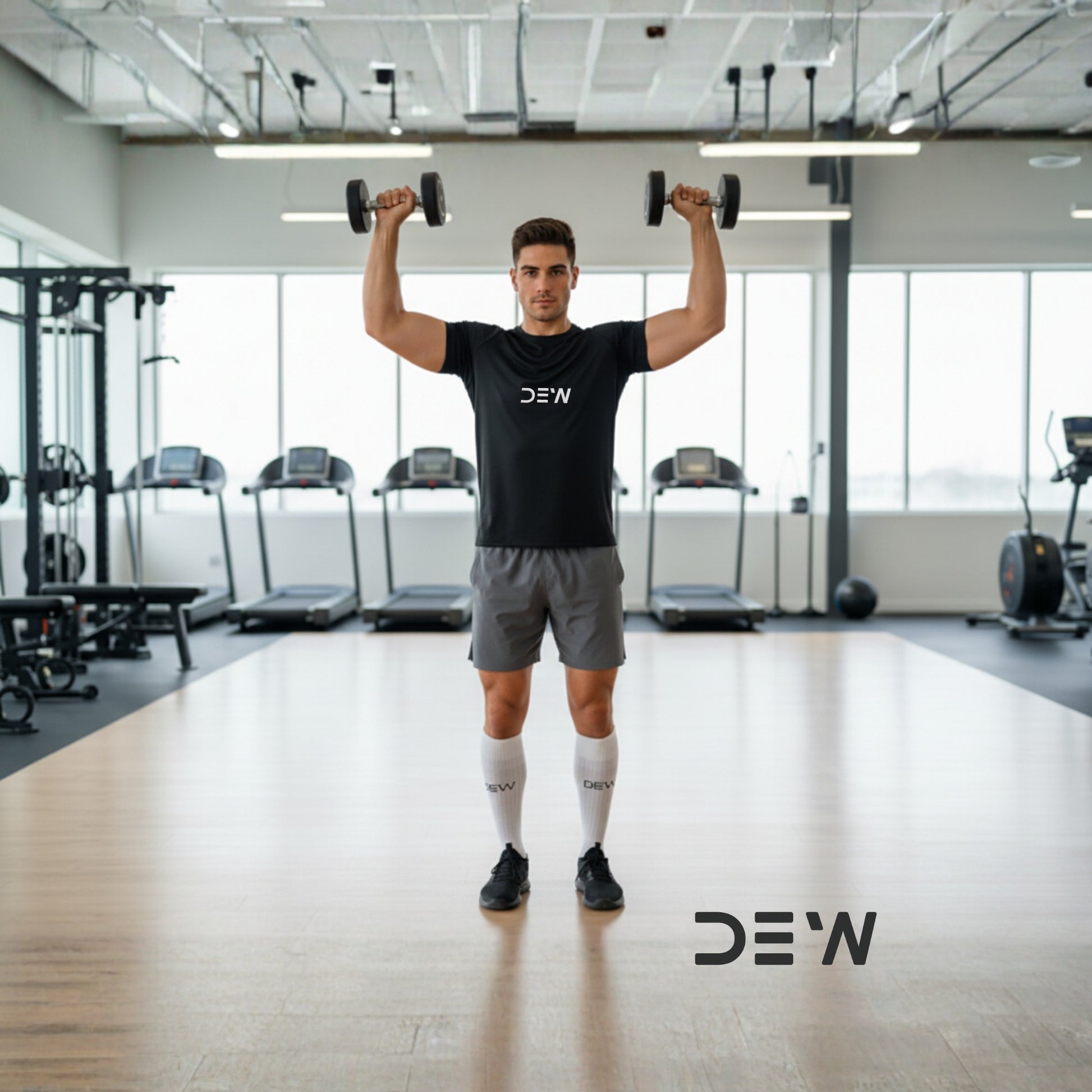 Man lifting dumbbells in black DEW T-Shirt and mid-calf bamboo socks in a gym.