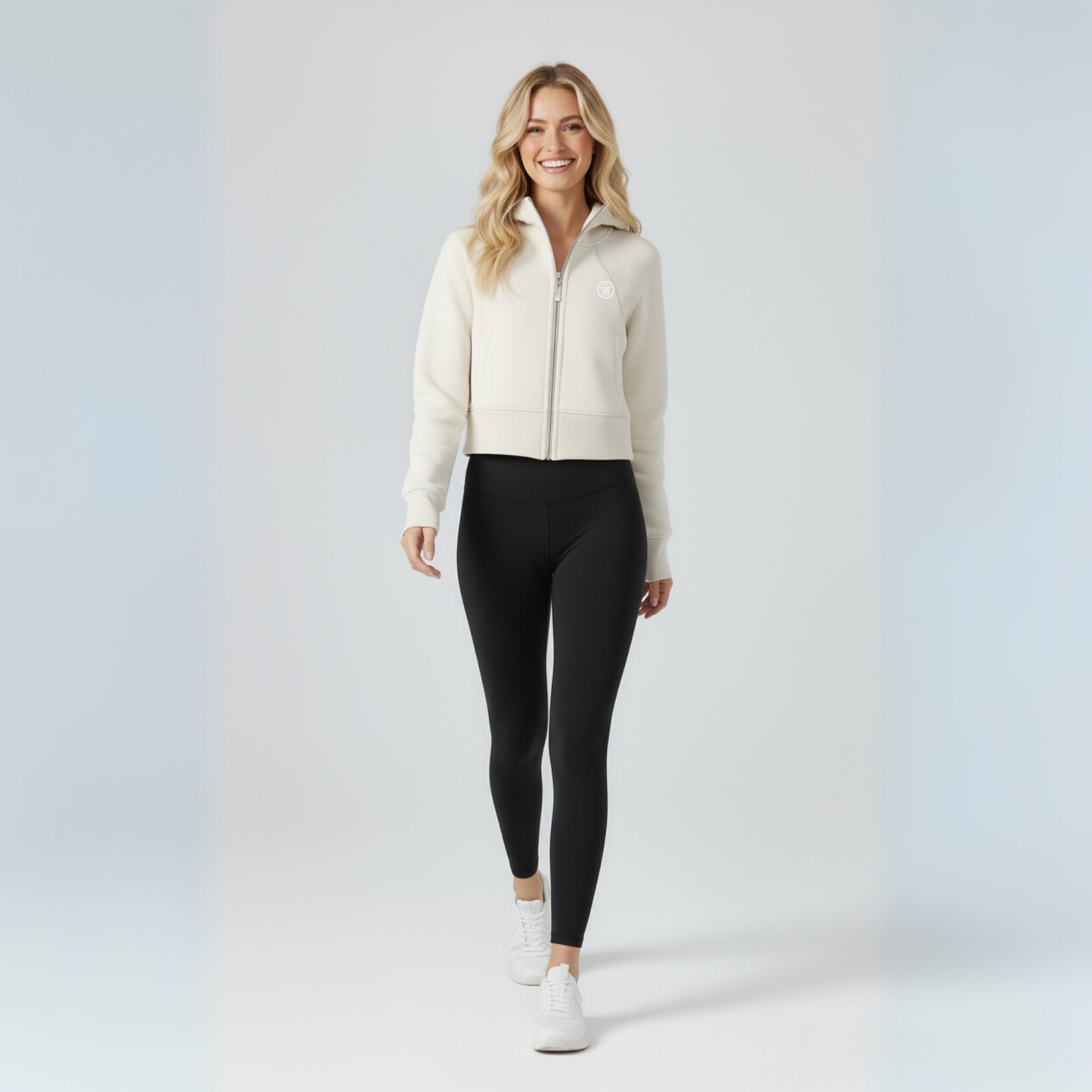 Woman wearing a white jacket and Dew black leggings on a light gray background