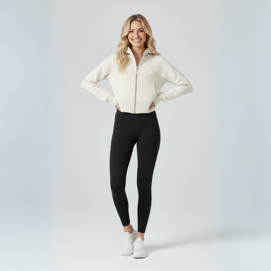 Woman wearing a white jacket, black dew leggings, and white sneakers on a light gray background