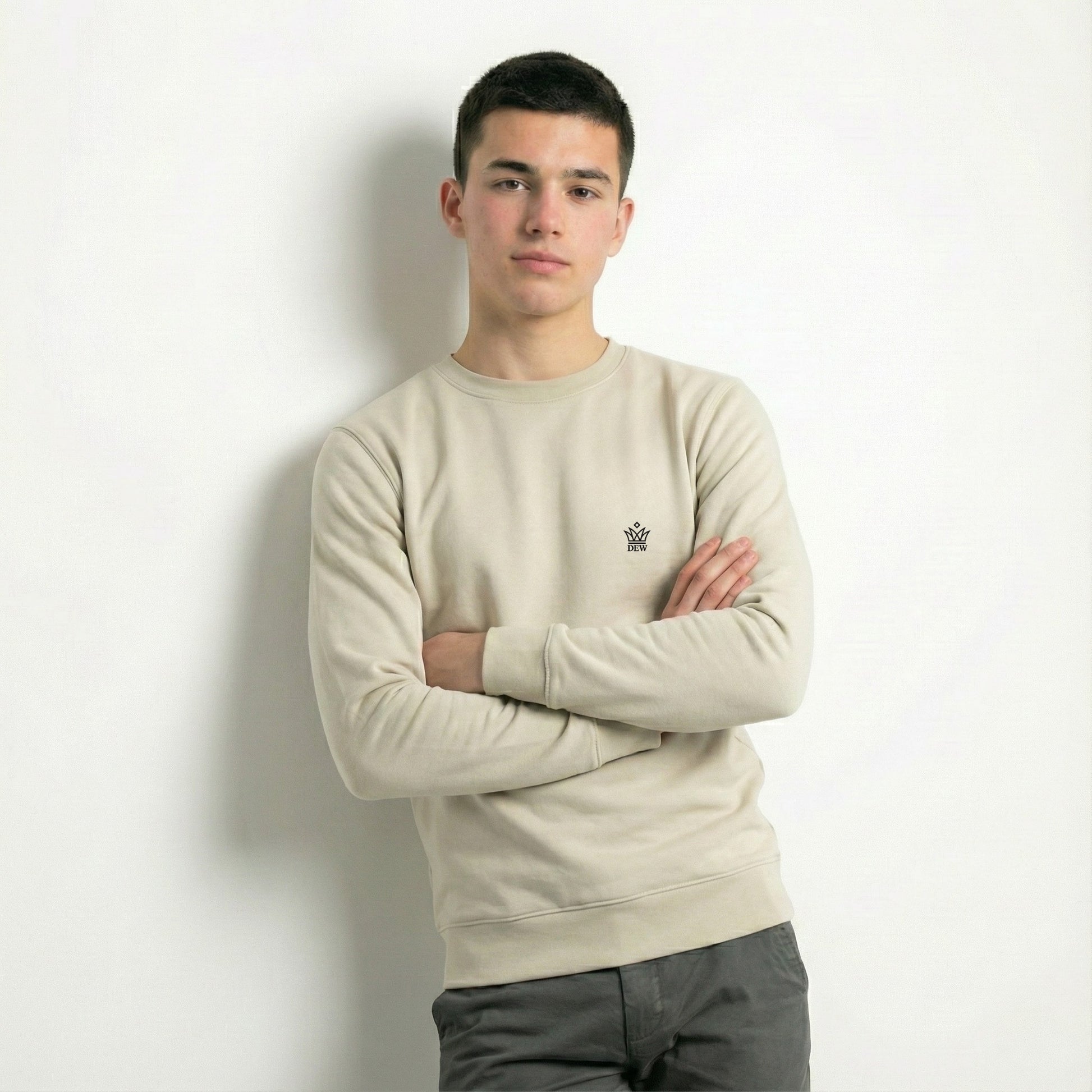 Person wearing a dew caramal jumper with a dew small logo, standing against a plain background