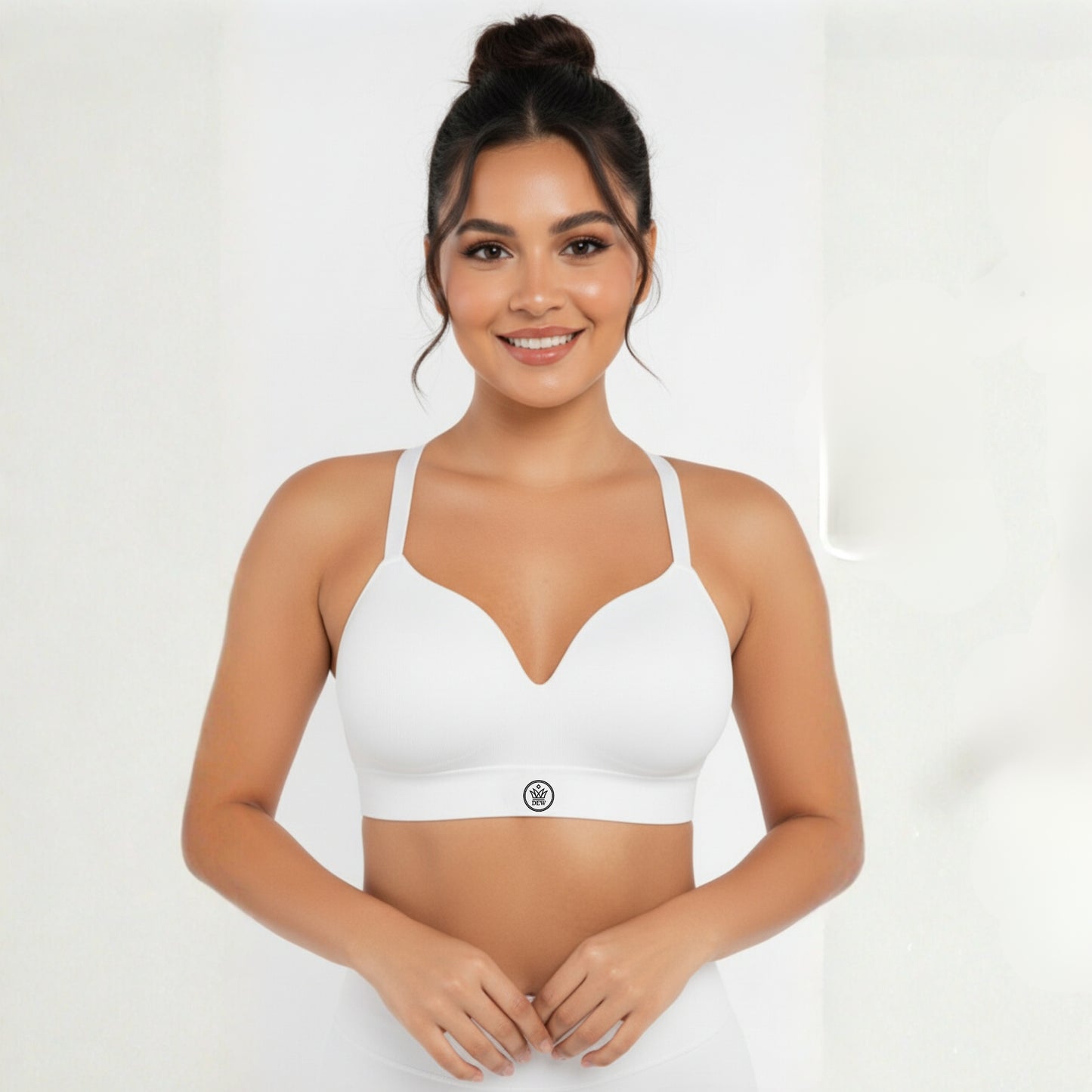 Woman wearing a white dew sports bra on a plain background