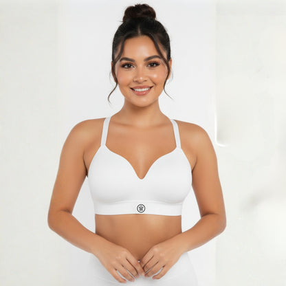 Woman wearing a white dew sports bra on a plain background