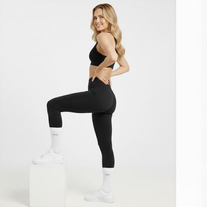 Woman in black athletic wear and Dew white socks posing on a white background