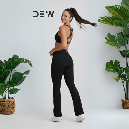 Woman wearing black seamless sports bra and Flow Fit Flare leggings. Minimalist studio setting, highlighting fit and flare design.