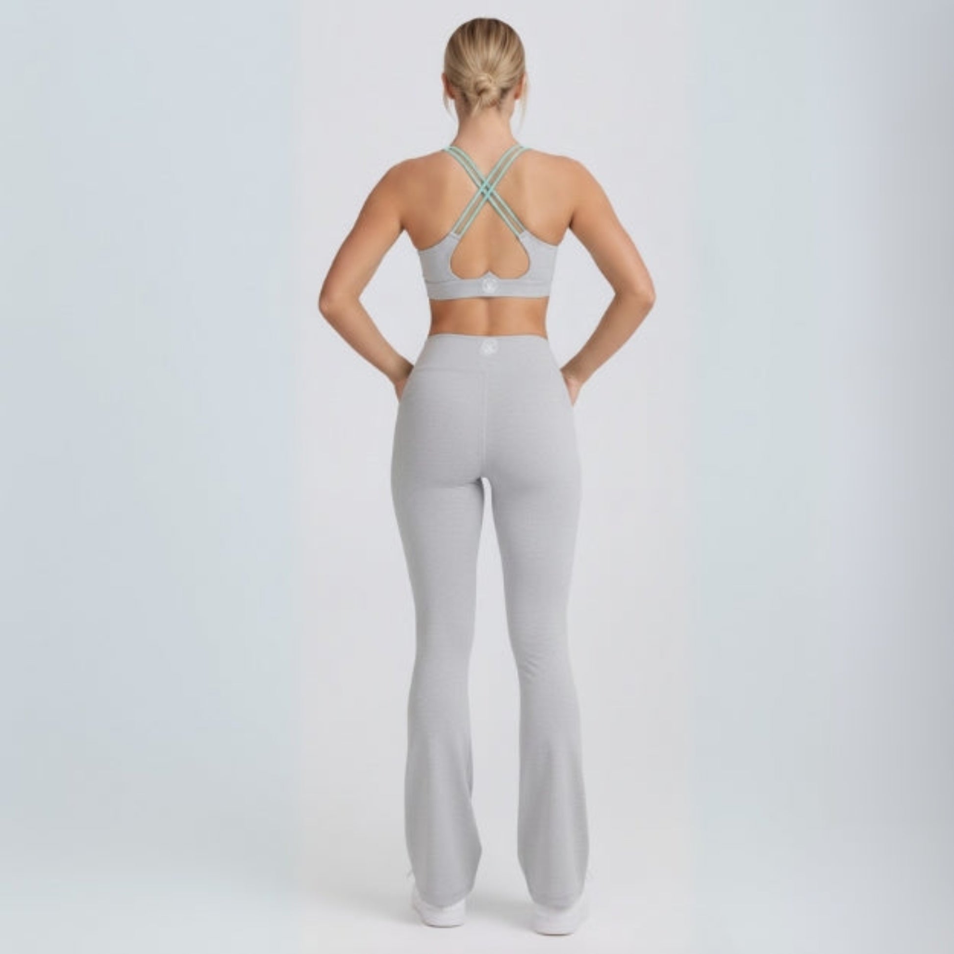 Person wearing a gray sports bra and Dew Flow fit flares leggings set on a white background