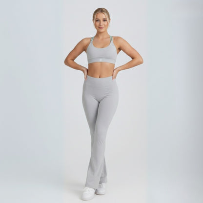 Woman wearing a gray Dew flow fit flares sports bra and leggings on a white background