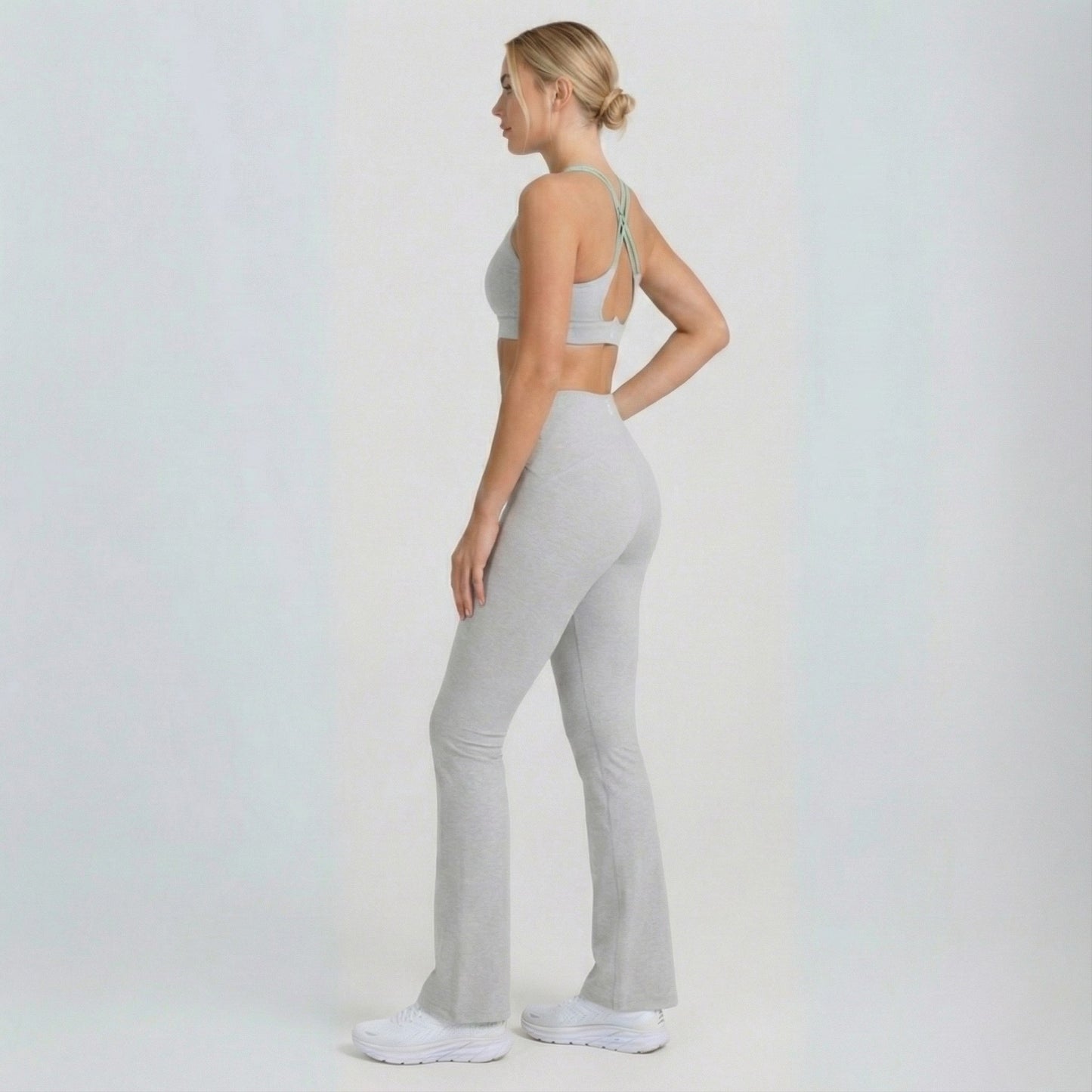 Woman wearing a gray sports bra and Dew Flow fit flares leggings on a white background