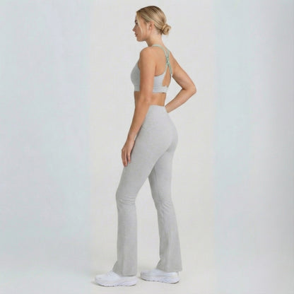 Woman wearing a gray sports bra and Dew Flow fit flares leggings on a white background