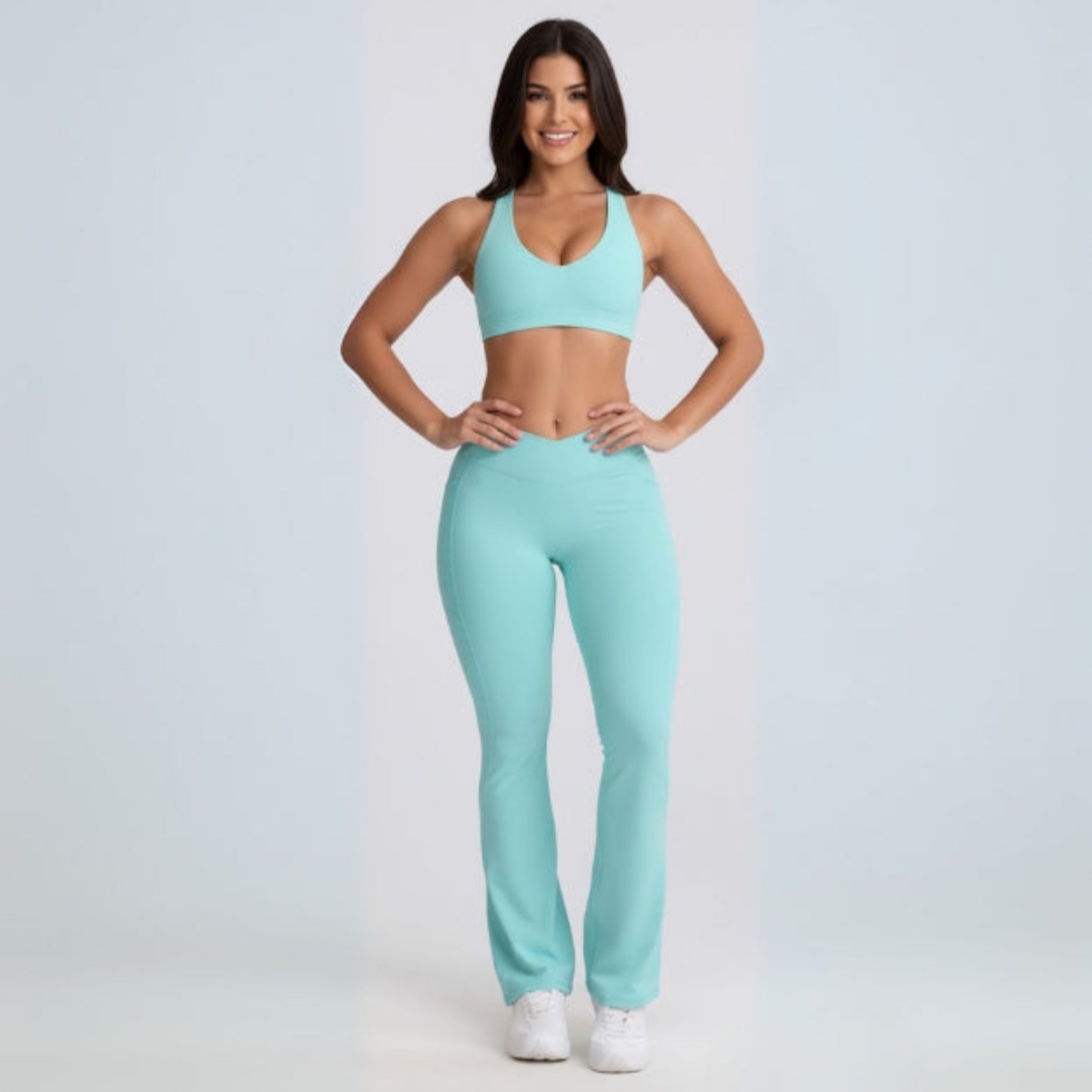 Woman wearing a matching Dew Flow fit flares sports bra and leggings set on a light gray background