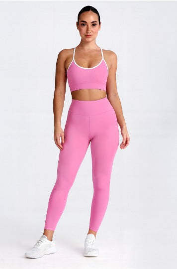Model wearing Pink Flow Fit Leggings and [Flow Fit Bra] stretching, showing the 4-way stretch and flattering high-waist fit.