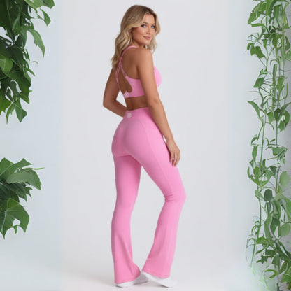 Woman wearing a pink Dew Flow fit flares outfit with plants on a white background