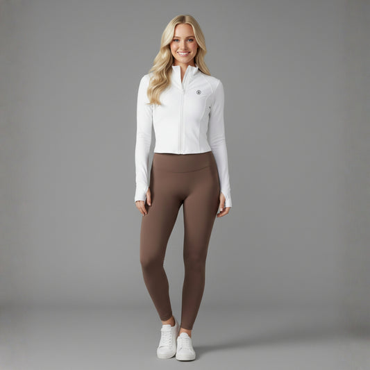 Woman wearing a white Dew Flex UPF50+ Performance jacket and brown leggings on a gray background